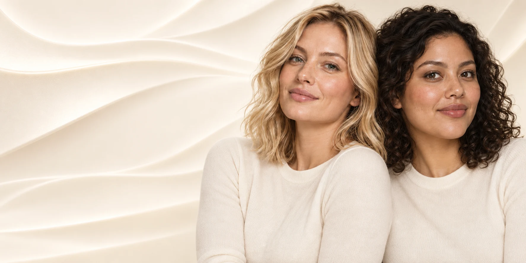 Two women in soft ivory knitwear against a flowing wave backdrop